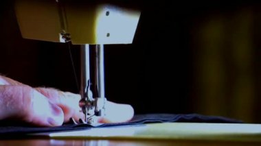 4k Yakın çekim. Bir terzi makinesiyle dikiş diker. Bir müşterinin giysisini dikerken işini profesyonelce yapıyor..