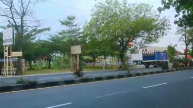 4k sokak manzaralı, yoğun bir anayoldaki kırmızı ışıkta trafiğin orta ve pürüzsüz olduğu bir saatte.