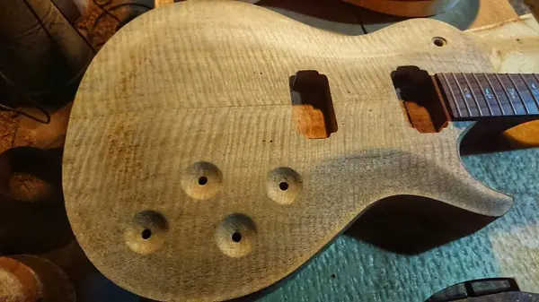 stock image Unfinished yet body, toping wood part and fretboard stock electric guitar handmade luthier craft workshop. 