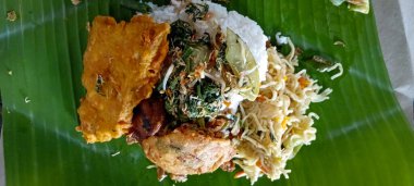 Kutlamaya başlamak için kutsanmış pirinç menüsü pirinç, erişte, manyok, baharat, ızgara tavuk ve muz yapraklarına sarılmış kızarmış yiyecekten oluşan geleneksel bir tarz.