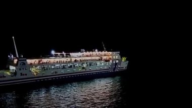 Merak, Cilegon, Banten, Endonezya, 25-09-2025: 4K Görüntülü deniz ulaşımı görülebilir, boğazdan geçen bir feribot, karanlık bir gecede renkli ışıklarla dolu