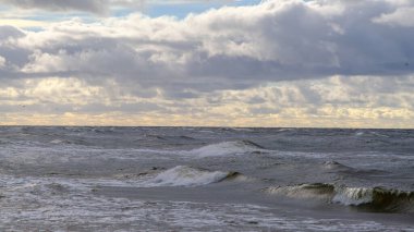 Baltık Denizi, gün batımında kayalar. Gece fırtınasından sonra küçük dalgalar.