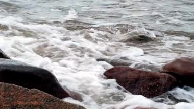 Denizin dalgası kayalara çarpıyor. Karanlık bir sonbahar günü