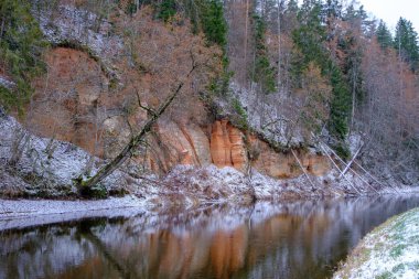 Salaca nehri yüksek kumtaşı kayalıklarıyla kıvrılır. Skanaiskalns Doğa Parkı. Kasım, Letonya 'da Mazsalaca' da ilk kar yağışıdır.