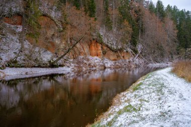 Salaca nehri yüksek kumtaşı kayalıklarıyla kıvrılır. Skanaiskalns Doğa Parkı. Kasım, Letonya 'da Mazsalaca' da ilk kar yağışıdır.