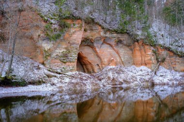 Nisan 'da Letonya' da Mazsalaca 'daki Skanaiskalns Doğa Parkı' ndaki Salaca nehrindeki kırmızı kumtaşı uçurumuna bakın..