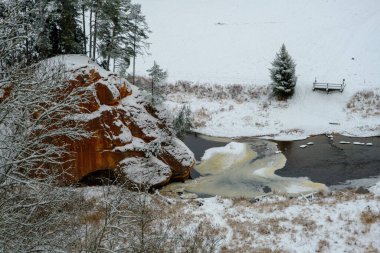 Kum taşı kayası. Zvartes, beyaz, karlı ve soğuk bir kış günü, Letonya 'daki Gauja Ulusal Parkı' nda Amata Nehri 'nin kıyısında kayalar çiziyor..