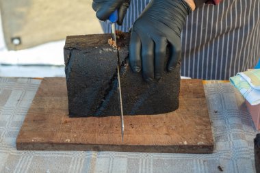 Bir kadının elleri ev yapımı bir markette ekmek kesiyor. Kadınlar için mavi lastik eldivenler