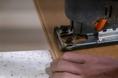 Installation of laminate in a room, a worker cuts a certain length of laminate with an electric saw. self-repair of floors in the house.