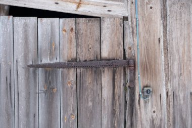 rusty old metal door hinge. Wooden barn door textured background with rusting metal hinge.