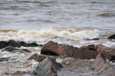 The waves of the Baltic Sea wash the stones of different sizes on the shore
