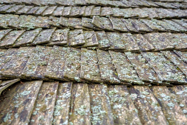 The old wooden texture of the roof, tile made of chipped wooden fragments. Traditional wooden roof tiles of an old European house.
