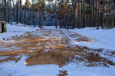 New road construction site in the forest in winter with snow and mud. Construction of new communications.