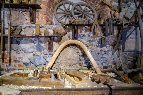大工道具の背景 昔ながらの錆びた大工の道具 テーブルの上の様々な道具 壁には木製の馬車があり — ストック写真