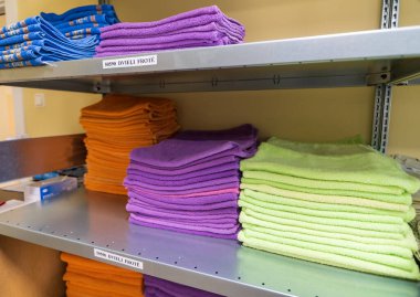 Temiz, yumuşak havlular farklı renklerde katlanmış ve yığılmış. Çamaşır odasındaki raflarda yığılmış havlular..