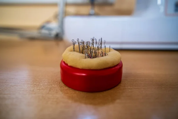 A lot of needles stuck in a soft material red container for storage.