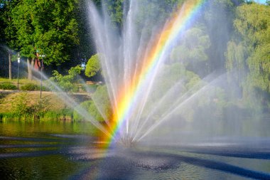 Güneşli bir günde çeşme. Çeşme damlası. Çeşmenin arka planında parlak gökkuşağı.