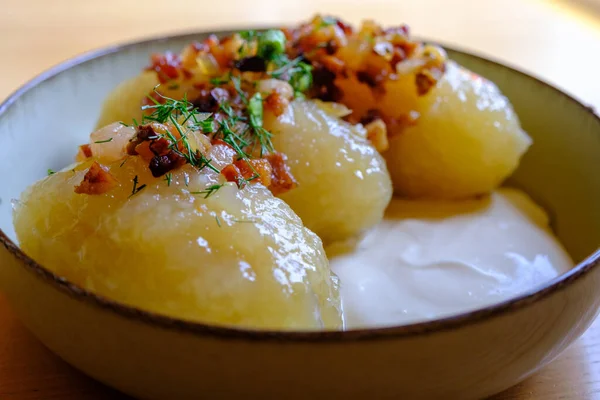 stock image Tasty, hearty traditional Lithuanian food served with cream and fried bacon, zeppelini made of grated potatoes with minced meat.