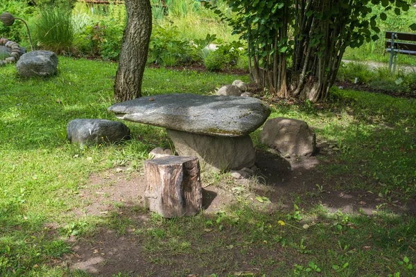 Resting place in the park. Picnic area in the garden. Stone picnic table with benches on a beautiful lawn in a quiet location. A beautiful picnic spot with a stone table in the summer garden.