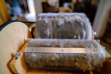 Wool felting. The step of combing the material in a special carding machine. Focus on foreground. clipart