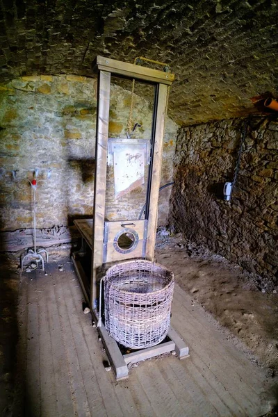 黑暗的地下室房间里几乎没有灯光 断头台是中世纪的一种惩罚工具 它是用柳条筐做的 — 图库照片