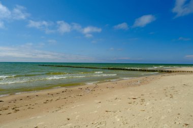 Arka planda mavi gökyüzü olan büyük bir körfezdeki eski ahşap iskelenin yan görüntüsü. Baltık Denizi Letonya.