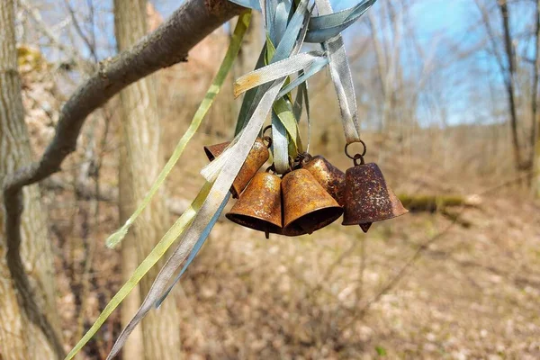 Small metal bells hung in the garden, a sunny spring day, decorated with different colored ribbons.