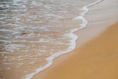 Sahildeki deniz suyu yaz arkaplanı. Kum plajı çöl dokusu. Beyaz köpüklü kumlu deniz manzaralı. Güneşli bir Eylül günü.
