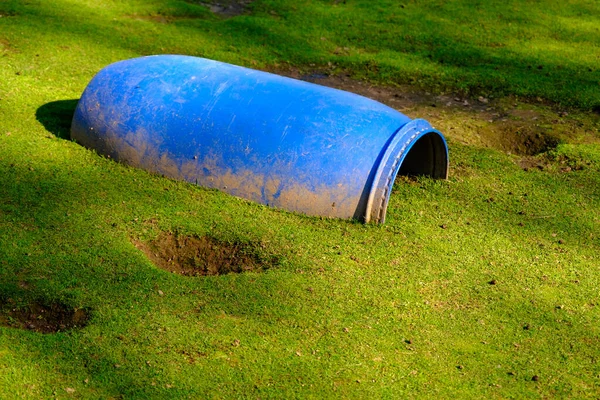 A large blue plastic barrel half buried in the ground. A place for small pets to hide.