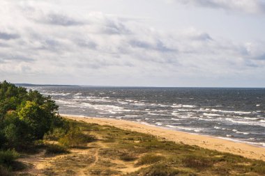 Letonya 'nın Baltık Denizi kıyı şeridi manzarası. Güneşli bir sonbahar gününde güzel bir deniz kıyısı. Deniz dalgaları. Letonya doğal manzarası. Rüzgarlı bir hava. Riga Körfezi.