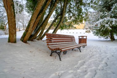 Kışın karda parkta kırmızı banklar var..