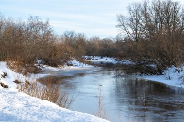 Kışın küçük dar bir nehir, nehir kıvrımı, su yansımaları.