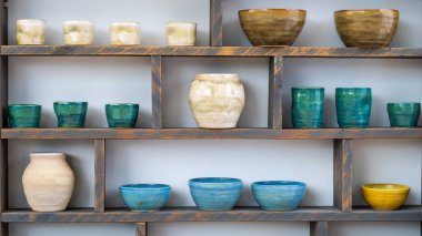 Değişik renkli seramik kaplar ve kaseler kırsal ahşap raflarda özgün camlarını ve tasarımlarını sergiliyorlar..