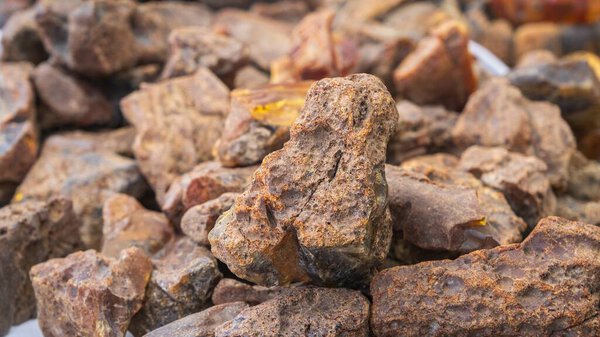 Детальное крупным планом изображение, демонстрирующее коллекцию грубых, неотполированных янтарных камней различных форм и размеров.