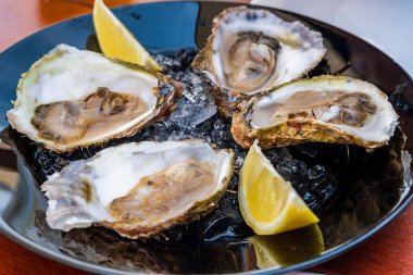 Limon dilimli taze istiridye tabağı yenmeye hazır, bu deniz ürünlerinin lezzetinin ve tazeliğinin altını çiziyor..