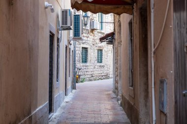 Kotor Körfezi, Karadağ - 22 Ağustos 2024: Taş binalar, klima üniteleri ve tarihi Akdeniz kasabasında sessiz bir patika ile çevrili dar bir sokak.