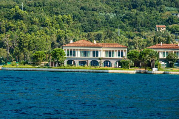 Залив Котор, Черногория - 22 августа 2024 года: Роскошная вилла на набережной со средиземноморской архитектурой, пышными садами и спокойной прибрежной обстановкой вблизи зеленых холмов и природы.