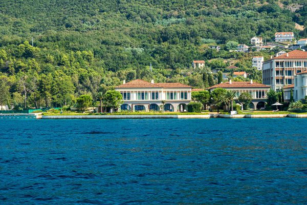 Залив Котор, Черногория - 22 августа 2024 года: Роскошные виллы на набережной со средиземноморской архитектурой, окруженные зелеными холмами, с которых открывается спокойный вид на море и природу.