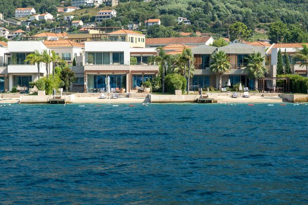 Залив Котор, Монтенегро - 22 августа 2024 года: Современные прибрежные виллы с прямым доступом к пляжу, удобствами и потрясающим видом на море, расположенные в спокойной прибрежной среде.