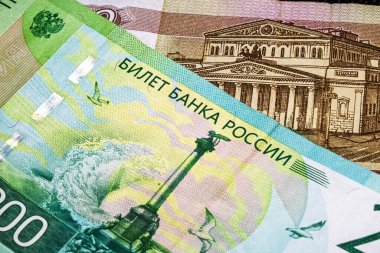 Rus banknotlarının yakın plan çekimleri, karmaşık tasarım unsurları, canlı renkler, metin ve tarihi simgeler, para birimi ve finansmanı temsil ediyor.