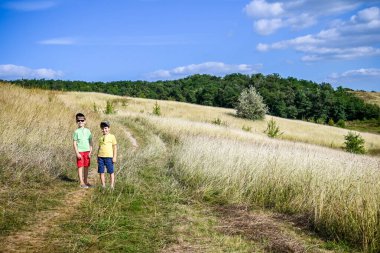 Two boys of school age are walking and admiring the view of the mountains, children in bright clothes. Travel with children summer concept.