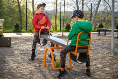 İki küçük çocuk dışarıda salıncakta sallanırken eğleniyor. Çocuklar, en iyi arkadaşlar ve kardeşler güneşli baharda ya da sonbahar gününde salıncakta sallanıyorlar. Çocuklarla aktif zaman geçirme. Sıradan erkek modası..