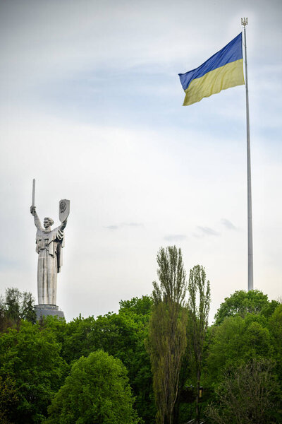 The flag of Ukraine next to the Motherland Statue in Kyiv.