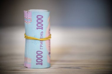 Yeni Ukrayna Hrivnia 'sı. 1000 Hryvnia ahşap masa üzerinde lastik bantla tüpe bağlanmış. para geçmişi ve zenginlik kavramı.
