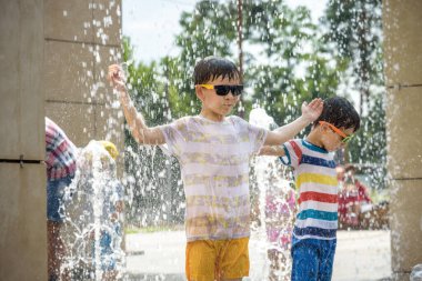 Boy having fun in water fountains. Child playing with a city fountain on hot summer day. Happy kids having fun in fountain. Summer weather. Active leisure, lifestyle and vacation.