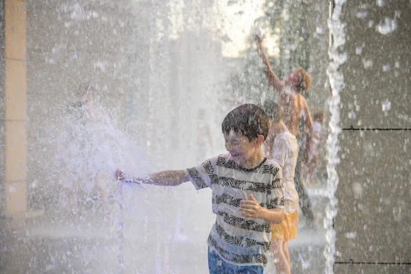 男孩子们跳进了水泉里 炎炎夏日 孩子们在城市的喷泉旁玩耍 快乐的朋友在喷泉里玩得开心 夏天的天气 生活方式和假期 — 图库照片