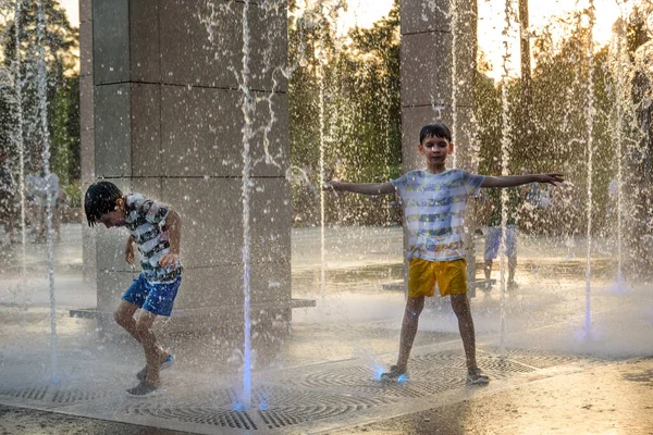 男孩子们跳进了水泉里 炎炎夏日 孩子们在城市的喷泉旁玩耍 快乐的朋友在喷泉里玩得开心 夏天的天气 生活方式和假期 — 图库照片