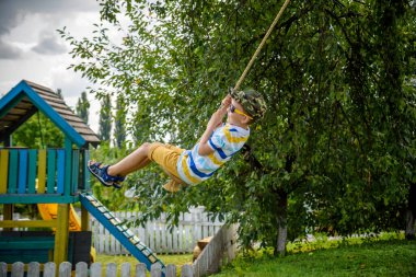 Mutlu küçük çocuk şehir dışında dinlenirken bulduğu bir salıncakta eğleniyor. Çocuklarla aktif boş zaman.