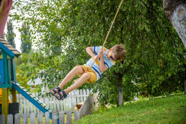 Mutlu küçük çocuk şehir dışında dinlenirken bulduğu bir salıncakta eğleniyor. Çocuklarla aktif boş zaman.