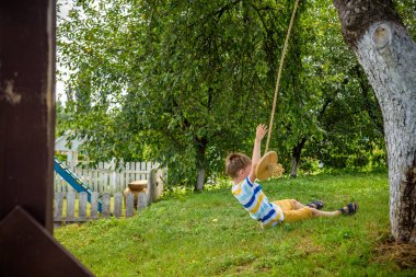 Mutlu küçük çocuk şehir dışında dinlenirken bulduğu bir salıncakta eğleniyor. Çocuklarla aktif boş zaman.